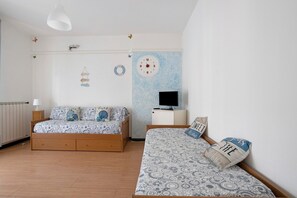 Camera da letto con due letti, una TV e un orologio a parete.