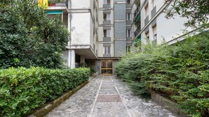 Un camino de piedra que lleva a la entrada de un edificio, rodeado de abundante vegetación.