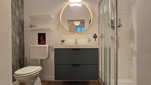 A modern bathroom with a toilet, sink, vanity, and shower.