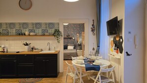 A compact kitchen with a sink, stove, and cabinets, leading to a dining area with a table set for two.