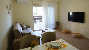 A modern living room with a sofa, dining table, and TV. - Margen Apartments - Tirana City Center (Tirana)