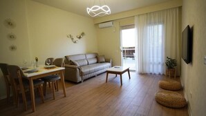 A living room with a sofa, a dining table with chairs, a coffee table, and a TV mounted on the wall. - Margen Apartments - Tirana City Center (Tirana)