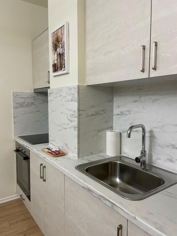 Una cocina moderna con encimeras de mármol, pileta de acero inoxidable y muebles de color claro.
