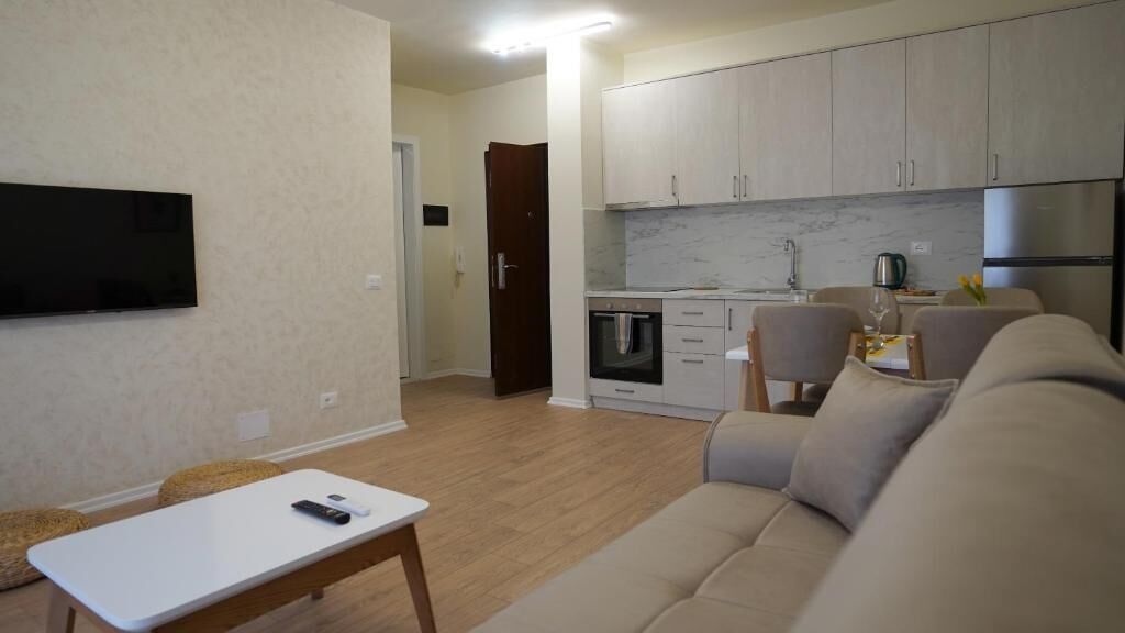 A modern living room with a sofa, a coffee table, and a TV mounted on the wall.