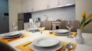 A dining table set with plates, cutlery, and wine glasses, with a vase of tulips on the table. - Margen Apartments - Tirana City Center (Tirana)