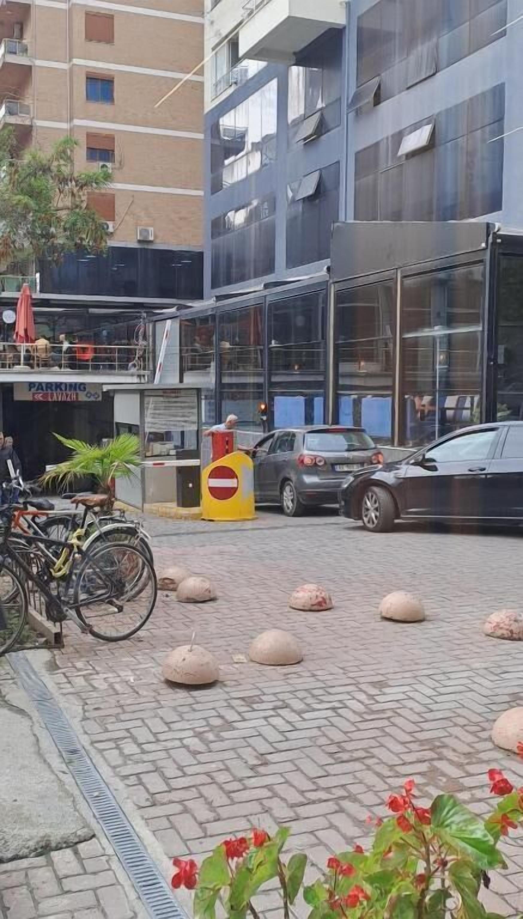 Een parkeerplaats met een auto, fietsen en paaltjes.