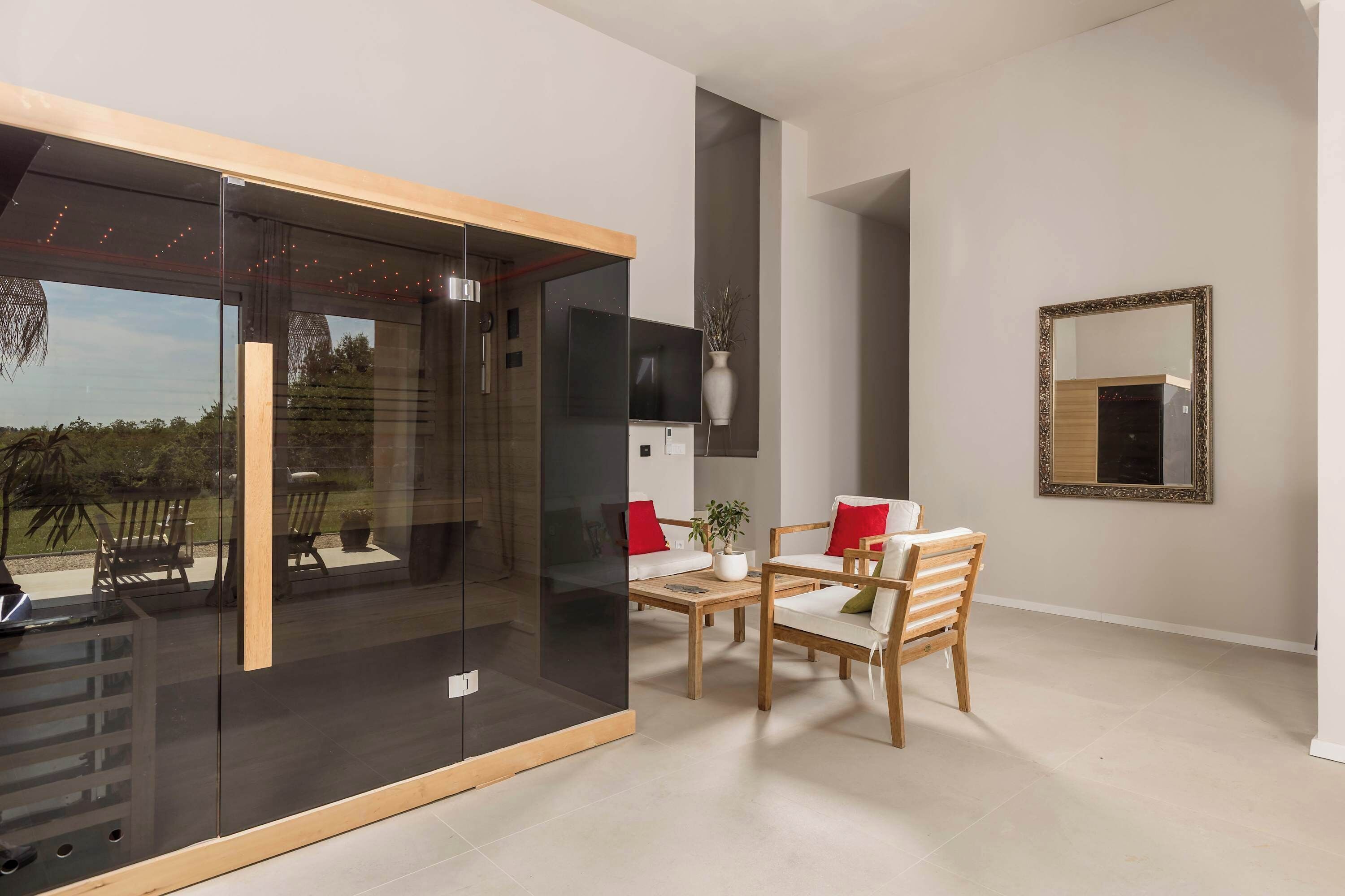 A modern room with a glass partition, wooden furniture, a flat-screen TV, and a mirror on the wall.