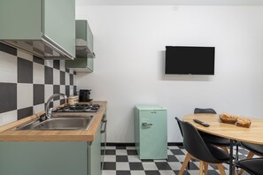 Una cocina compacta con un lavamanos, estufa y un refrigerador pequeño.