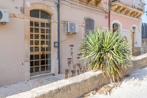 Um edifício com uma grande janela em arco, um aparelho de ar condicionado e uma planta em primeiro plano.