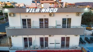 A building with 'VILA NAO' signage, balconies, and a pool area. - Vila Naço Ksamil (Ksamil)