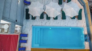 A swimming pool with blue water, surrounded by green lounge chairs and white crocheted umbrellas. - Vila Naço Ksamil (Ksamil)