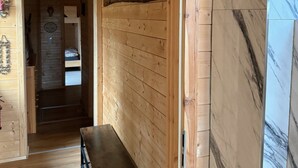 A wooden interior with a bench, a door leading to a bedroom, and a marble wall. - Idyllic House in the Harz Mountains (Harzgerode)