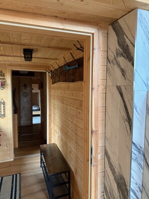 Un interno in legno con una panca, una porta che dà su una camera da letto e un muro in marmo.