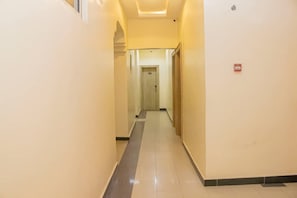 A narrow, well-lit hallway with a tiled floor and a door at the end. - Correct Residence & Resort (Abuja)