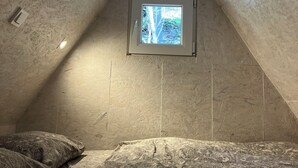A small attic bedroom with a sloped ceiling, a skylight, and a hanging dreamcatcher. - Tiny house in Posázaví region (Kaliště-Ondřejov)