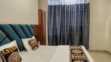 Quarto com cama, almofadas, ventoinha no teto e cortinas.
