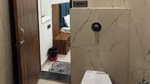 A bathroom with a toilet, a shower, and a wooden wardrobe.