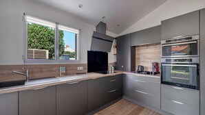 Una cocina moderna con un amplio ventanal, electrodomésticos integrados y suelo de madera.