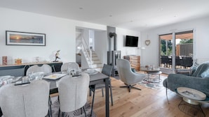 Una sala de estar moderna con comedor, chimenea y televisor montado en la pared.