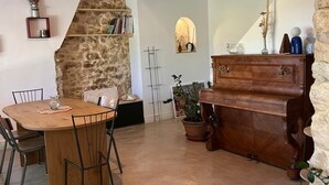 Een rustieke eethoek met een houten tafel en stoelen, een stenen muur en een houten piano.