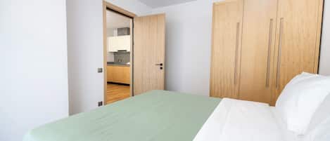 A bedroom with a bed, a wardrobe, and a door leading to a bathroom.