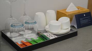 A tray with wine glasses, cups, and a tissue box on a counter.