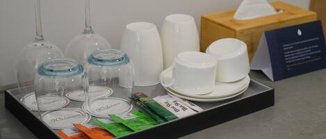 Una bandeja con copas de vino, tazas y una caja de pañuelos sobre una encimera.