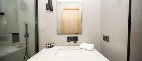 A modern bathroom with a large mirror, a sink, and a towel rack.