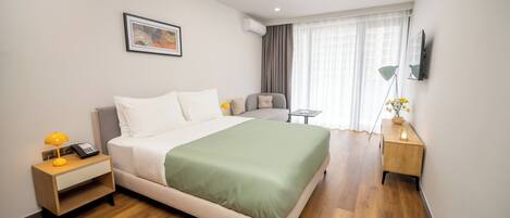 Una habitación de hotel moderna con una cama grande, mesitas de noche, un escritorio y una ventana con cortinas.
