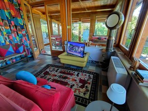 A cozy living room with a television, a fireplace, and a view of the outdoors.