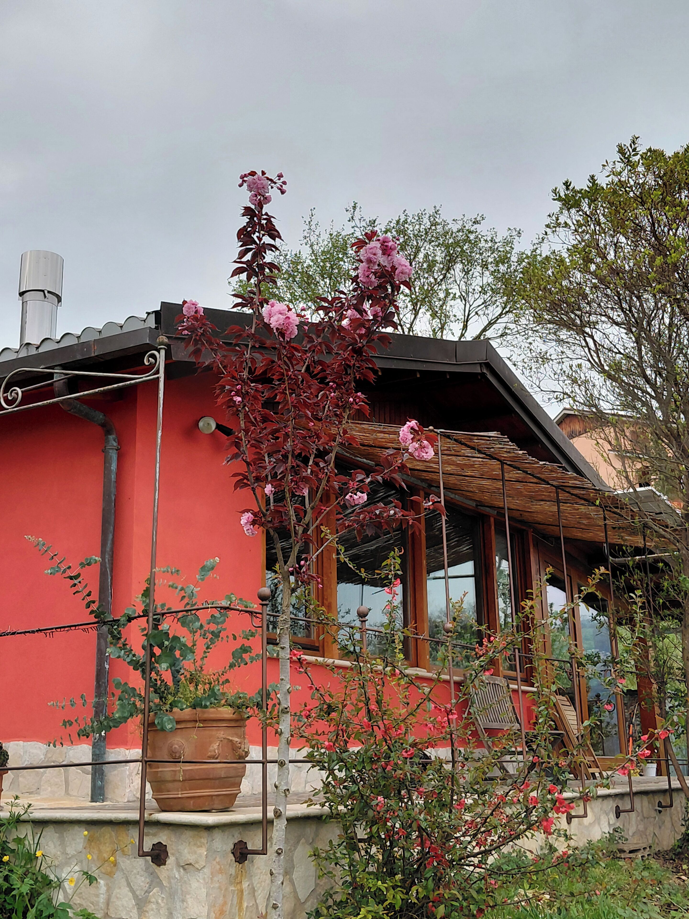 Ein rotes Gebäude mit Balkon, Schornstein und Blumentöpfen.