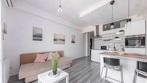 Une cuisine moderne dotée d’un îlot central, de meubles blancs et d’un coin repas avec des tabourets de bar.
