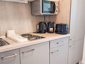 A modern kitchen with a microwave, coffee maker, and kettle on the counter. - Lovely apartment for 3 people with WIFI, A/C, TV and balcony (Strobl)