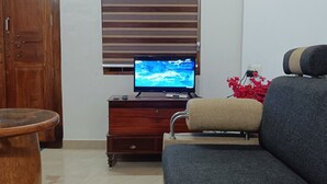 A living room with a wooden cabinet, a television, a sofa, and a small round table. - River Soul Villa/ 3-bedroom house in Riverside (Upputhara)