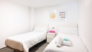 Habitación de hotel con dos camas individuales, una mesita de noche con un teléfono rosa y una obra de arte en la pared que representa caballos.