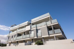 A multi-story residential building with balconies, large windows, and a flat roof.