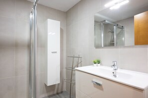 A modern bathroom with a glass shower enclosure, a white sink, and a mirror above it.