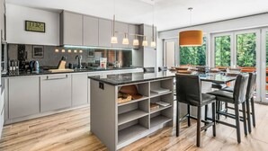 Een moderne keuken met grijze kastjes, een centraal eiland en hanglampen.