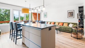 Een moderne keuken met een centraal eiland, barkrukken en hanglampen.