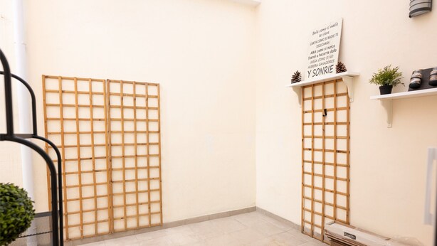 A room with a tiled floor, a wooden lattice partition, a shelf with potted plants, and a sign with text. - Maravilloso Duplex en el Corazón de SC (Santa Cruz de Tenerife)