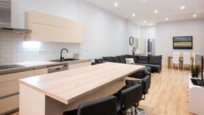 A modern kitchen with a central island, a dining area with a wooden table, and a living space with a sofa and chairs. - Maravilloso Duplex en el Corazón de SC (Santa Cruz de Tenerife)
