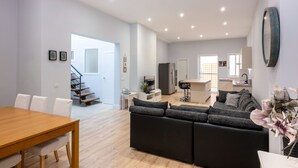 A spacious living area with a wooden dining table, a grey sofa, and a kitchen in the background. - Maravilloso Duplex en el Corazón de SC (Santa Cruz de Tenerife)