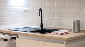 A modern kitchen with a black sink, a dish rack, and a stainless steel container. - Maravilloso Duplex en el Corazón de SC (Santa Cruz de Tenerife)