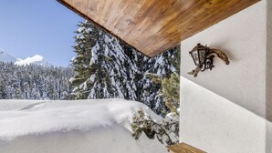 A snow-covered outdoor area with a wooden bench and a wall-mounted lantern.