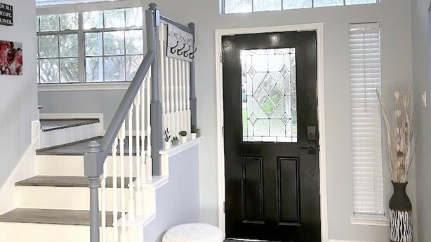 A modern interior with a staircase, a black door, and multiple windows. - Modern 4BR Retreat Extended Stay Ideal. SW Houston (Sugar Land)