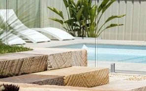 A pool area with stone steps leading into the water, surrounded by a white fence and greenery. - Illaroo House · Heated pool · Pets · Sleeps 10 (Shoal Bay)