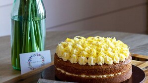 A cake with yellow frosting and a vase of yellow flowers on a wooden table. - Wonderful  villa for 4 guests with hot tub, terrace and pets allowed (Banbury)