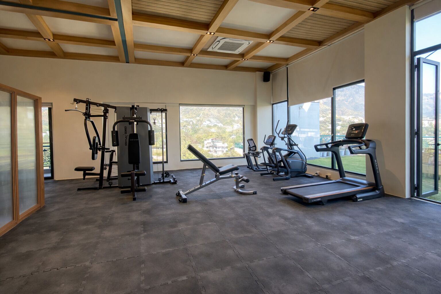 A gym with exercise equipment, large windows, and a high ceiling.