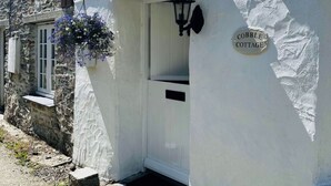 Ein weißes Cottage mit einem Schild, auf dem 'COBBLE COTTAGE' steht.