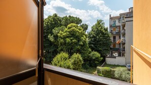 Vista desde un balcón que da a un patio con árboles frondosos y edificios de varios pisos.